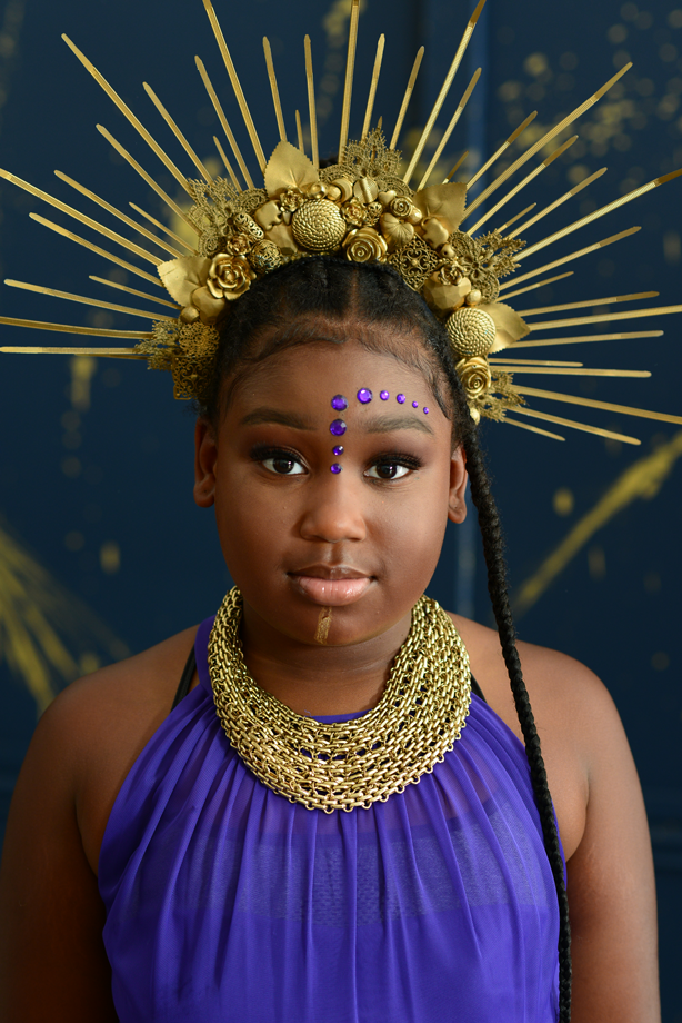 Beautiful Black Girl wearing a golden crown and royal purple dress